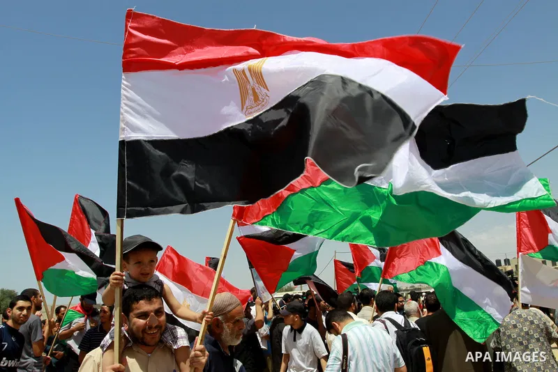 Palestinians wave with their national flag and Egyptian flag at Rafah border crossing in the southern Gaza Strip on May 28, 2011 as Egypt reopened the border, allowing people to cross freely for the first time in four ye...