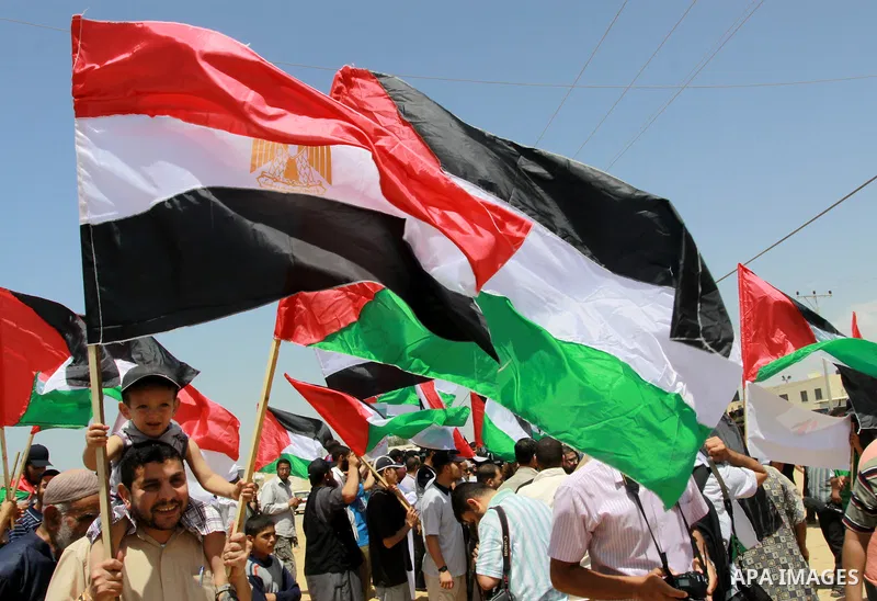 Palestinians wave with their national flag and Egyptian flag at Rafah border crossing in the southern Gaza Strip on May 28, 2011 as Egypt reopened the border, allowing people to cross freely for the first time in four ye...