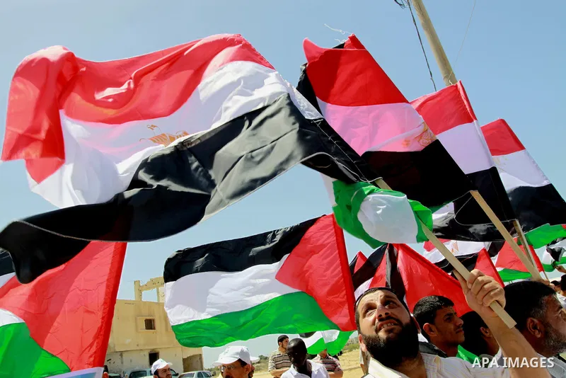 Palestinians wave with their national flag and Egyptian flag at Rafah border crossing in the southern Gaza Strip on May 28, 2011 as Egypt reopened the border, allowing people to cross freely for the first time in four ye...