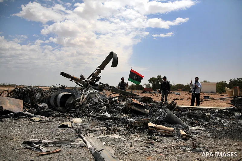 Libyan rebel fighters stand near a destroyed fighter plane belonging to forces loyal to Muammar Gaddafi at the airport of Misrata, Libya, May 28, 2011. Photo by Wissam Nassar