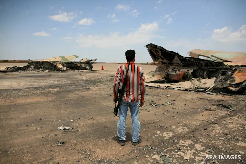 Libyan rebel fighters stand near a destroyed fighter plane belonging to forces loyal to Muammar Gaddafi at the airport of Misrata, Libya, May 28, 2011. Photo by Wissam Nassar