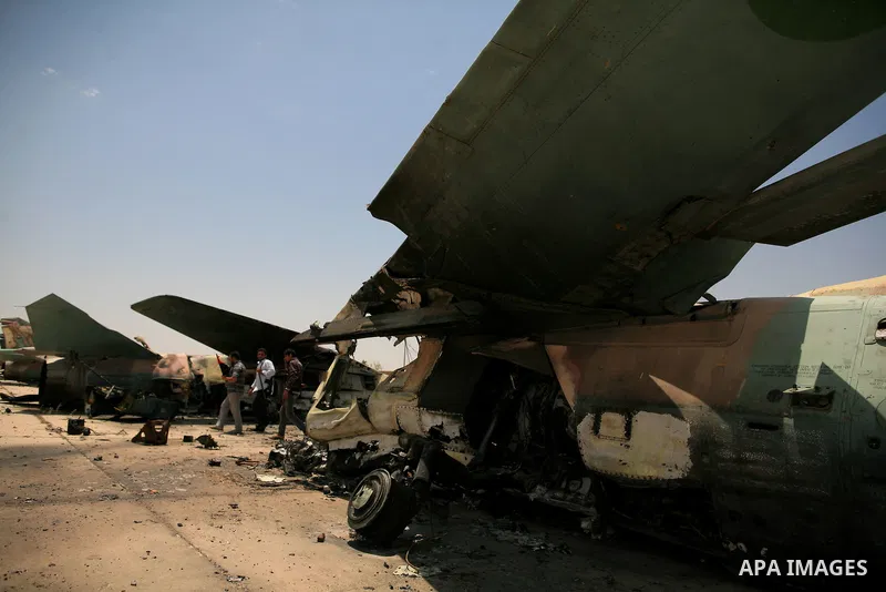 Libyan rebel fighters stand near a destroyed fighter plane belonging to forces loyal to Muammar Gaddafi at the airport of Misrata, Libya, May 28, 2011. Photo by Wissam Nassar
