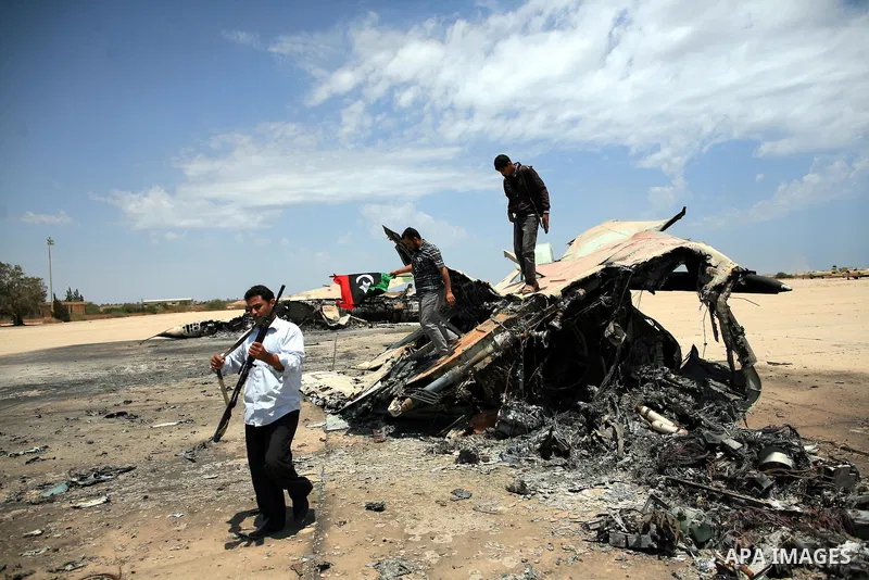 Libyan rebel fighters stand near a destroyed fighter plane belonging to forces loyal to Muammar Gaddafi at the airport of Misrata, Libya, May 28, 2011. Photo by Wissam Nassar