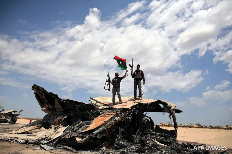 Libyan rebel fighters stand near a destroyed fighter plane belonging to forces loyal to Muammar Gaddafi at the airport of Misrata, Libya, May 28, 2011. Photo by Wissam Nassar