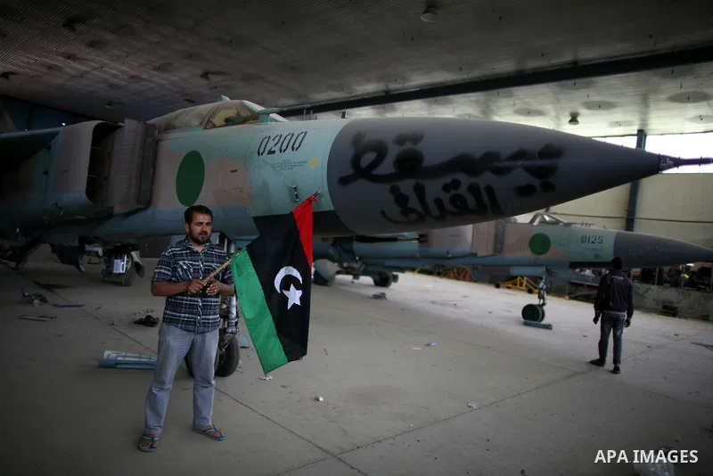 Libyan rebel fighters stand near fighter planes belonging to forces loyal to Muammar Gaddafi at the airport of Misrata, Libya, May 28, 2011. Photo by Wissam Nassar