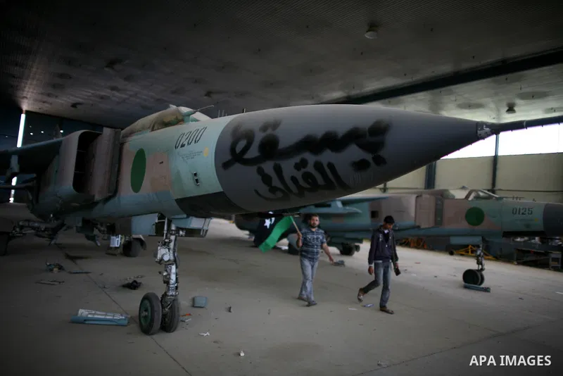Libyan rebel fighters stand near fighter planes belonging to forces loyal to Muammar Gaddafi at the airport of Misrata, Libya, May 28, 2011. Photo by Wissam Nassar