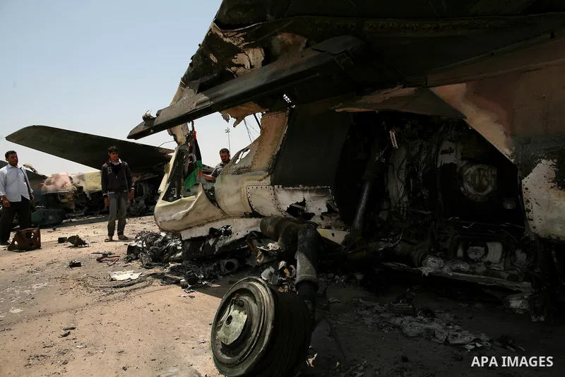Libyan rebel fighters stand near a destroyed fighter plane belonging to forces loyal to Muammar Gaddafi at the airport of Misrata, Libya, May 28, 2011. Photo by Wissam Nassar