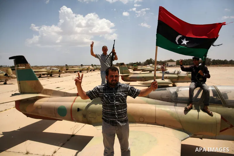Libyan rebel fighters stand near fighter planes belonging to forces loyal to Muammar Gaddafi at the airport of Misrata, Libya, May 28, 2011. Photo by Wissam Nassar