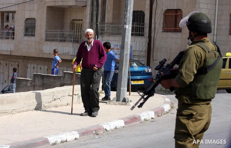 Israeli border guards stand guard near Palestinian civilians during a raid in the West Bank city of Ramallah on May 30, 2011. Five Palestinians were arrest, three from the village of Amrine, near the northern West Bank c...