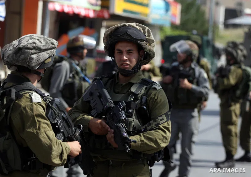 Israeli border guards stand guard near Palestinian civilians during a raid in the West Bank city of Ramallah on May 30, 2011. Five Palestinians were arrest, three from the village of Amrine, near the northern West Bank c...