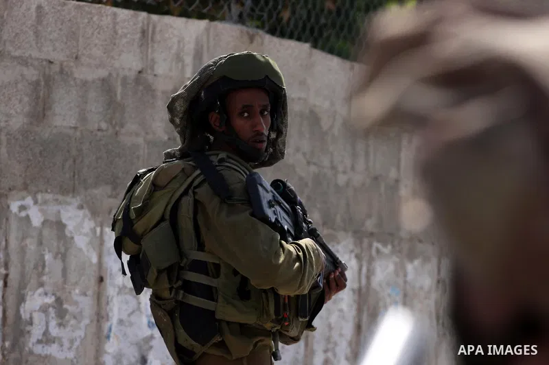 Israeli border guards stand guard near Palestinian civilians during a raid in the West Bank city of Ramallah on May 30, 2011. Five Palestinians were arrest, three from the village of Amrine, near the northern West Bank c...
