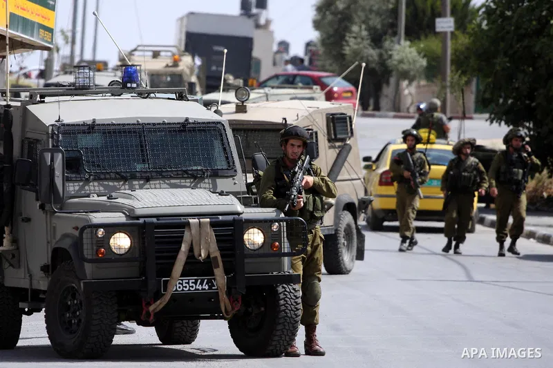 Israeli border guards stand guard near Palestinian civilians during a raid in the West Bank city of Ramallah on May 30, 2011. Five Palestinians were arrest, three from the village of Amrine, near the northern West Bank c...