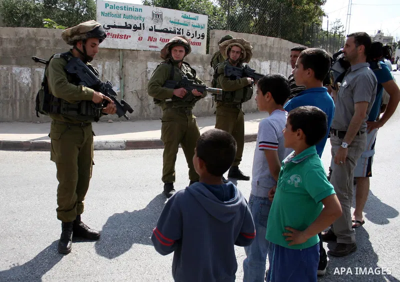 Israeli border guards stand guard near Palestinian civilians during a raid in the West Bank city of Ramallah on May 30, 2011. Five Palestinians were arrest, three from the village of Amrine, near the northern West Bank c...