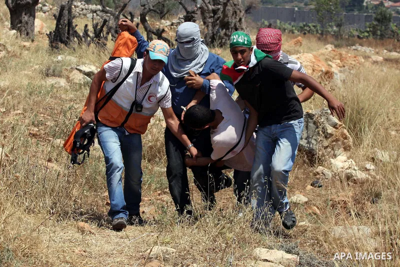 Palestinian demonstrators carry a wounded youth during a protest against Israel's separation barrier in the West Bank village of Nilin, near Ramallah, Friday, June 3, 2011. Photo by Issam Rimawi