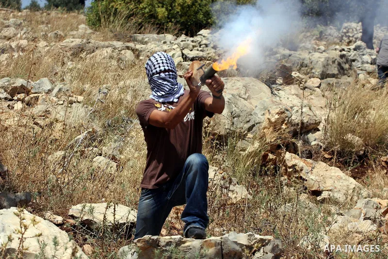 A Palestinian demonstrator fires a tear gas canister using a hand-made launcher towards Israeli troops during a protest against Israel's separation barrier in the West Bank village of Nilin, near Ramallah, Friday, June 3...