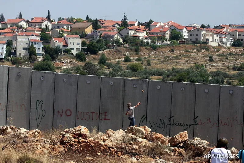 A Palestinian demonstrator throws stones to Israeli troops, not seen, during a protest against Israel's separation barrier in the West Bank village of Nilin, near Ramallah, Friday, June 3, 2011. Photo by Issam Rimawi