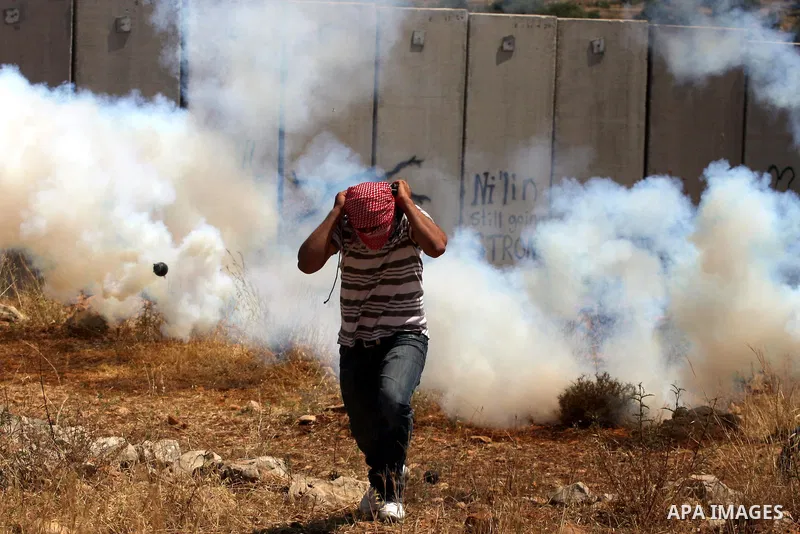 A Palestinian demonstrator runs for cover from tear gas canister fired by Israeli soldiers, not seen, during a protest against Israel's separation barrier in the West Bank village of Nilin, near Ramallah, Friday, June 3,...