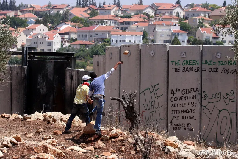 A Palestinian demonstrator throws stones to Israeli troops, not seen, during a protest against Israel's separation barrier in the West Bank village of Nilin, near Ramallah, Friday, June 3, 2011. Photo by Issam Rimawi