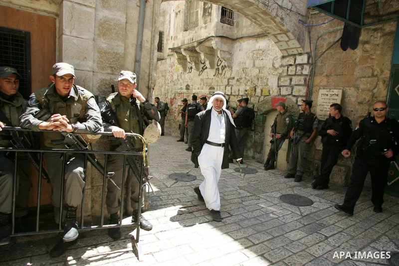 A Palestinian Muslim worshiper walk past Israeli soldiers after Friday prayer in Jerusalem's Old City on June 03, 2011 as Israeli police restricted the entrance age to men over 45 at the Al Aqsa Mosque compound in fear o...