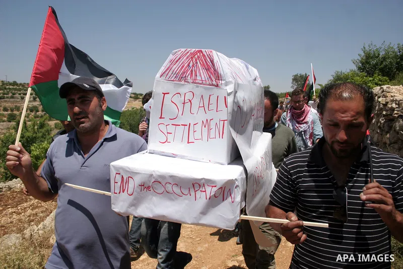 Israeli soldiers stand guard as Palestinians hold up a model of Jewish settlement during a demonstration by foreign, Israeli and Palestinian activists against the Jewish settlement of Karmei Tzur near the Palestinian vil...