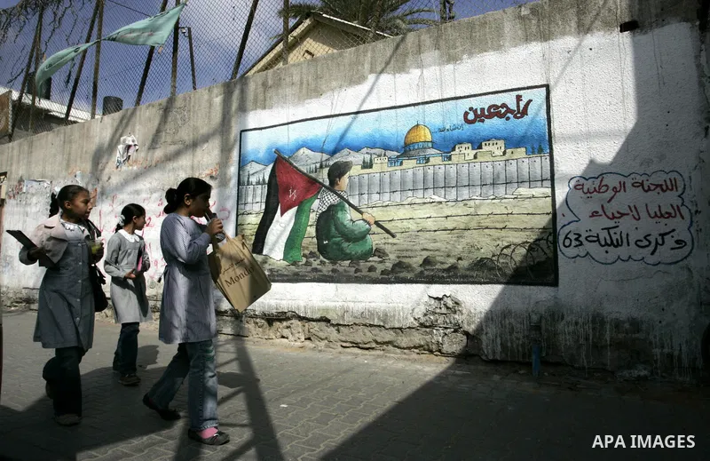 Palestinian girls walk in front of a mural painting on the theme of return of refugees in Rafah in southern Gaza Strip on June 5, 2011. Today sunday marking the 44th anniversary of 'Naksa,' Arabic for setback, of the ann...