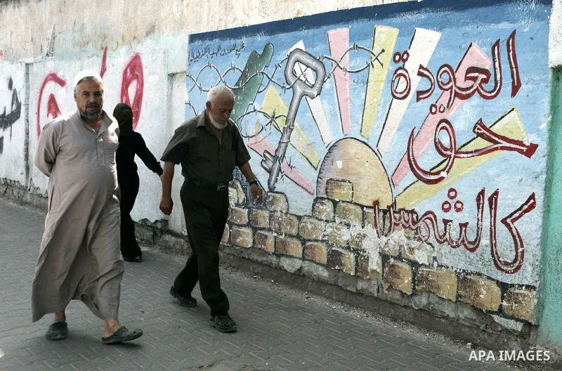 Palestinian men walk in front of a mural painting on the theme of return of refugees in Rafah in southern Gaza Strip on June 5, 2011. Today sunday marking the 44th anniversary of 'Naksa,' Arabic for setback, of the annex...