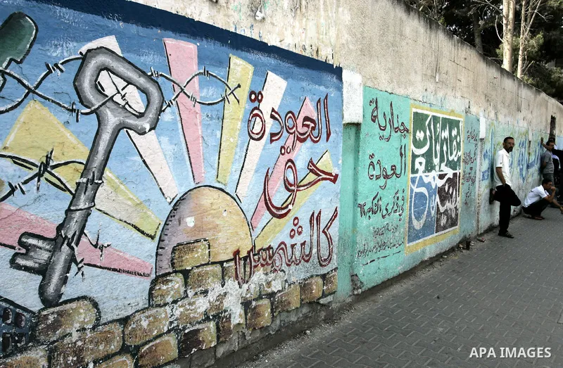 Palestinian men stand in front of a mural painting on the theme of return of refugees in Rafah in southern Gaza Strip on June 5, 2011. Today sunday marking the 44th anniversary of 'Naksa,' Arabic for setback, of the anne...