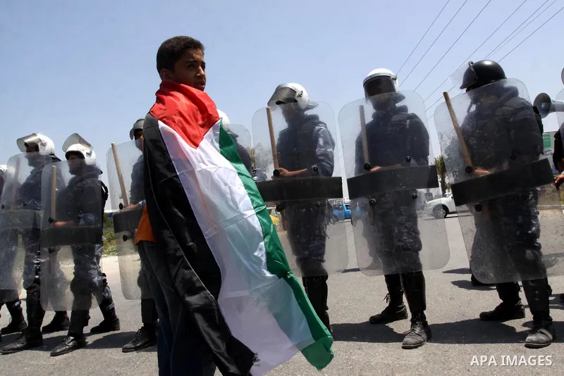 A Palestinian boy defied his small body and stands in front of Members of Hamas' security forces and hold Palestinian national flag during a demonstration when Hamas security forces holds back protesters from reaching Er...