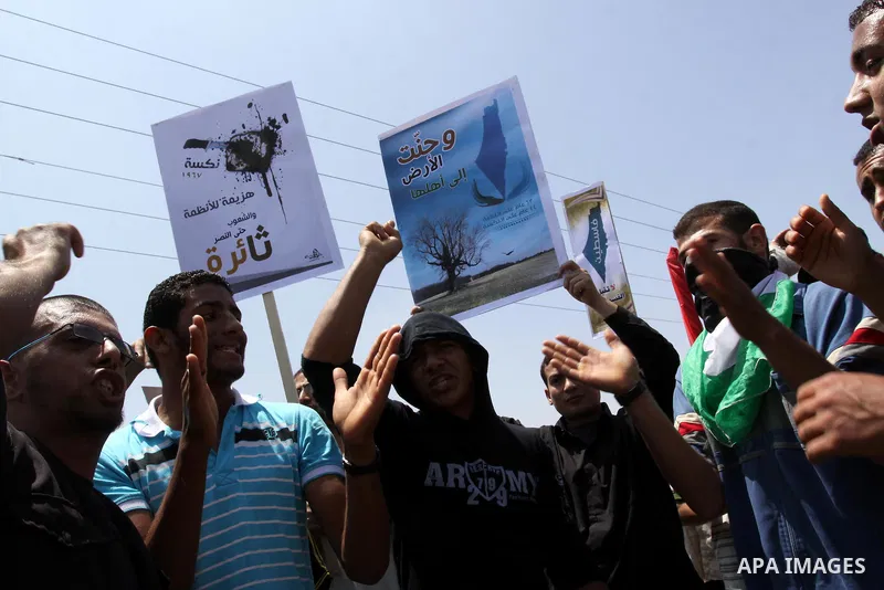 Palestinian protesters wave banners and Palestinian national flags during a demonstration and Members of Hamas' security forces holds back protesters from reaching Erez border crossing in the northern Gaza Strip, on June...
