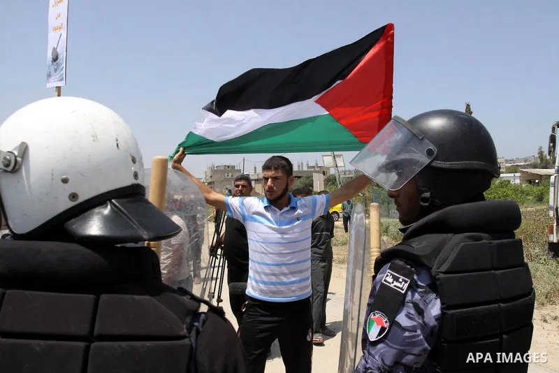 A Palestinian man stands in front of Members of Hamas' security forces and hold Palestinian national flag during a demonstration when Hamas security forces holds back protesters from reaching Erez border crossing in the...