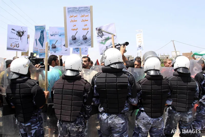 Palestinian protesters wave banners and Palestinian national flags during a demonstration and Members of Hamas' security forces holds back protesters from reaching Erez border crossing in the northern Gaza Strip, on June...