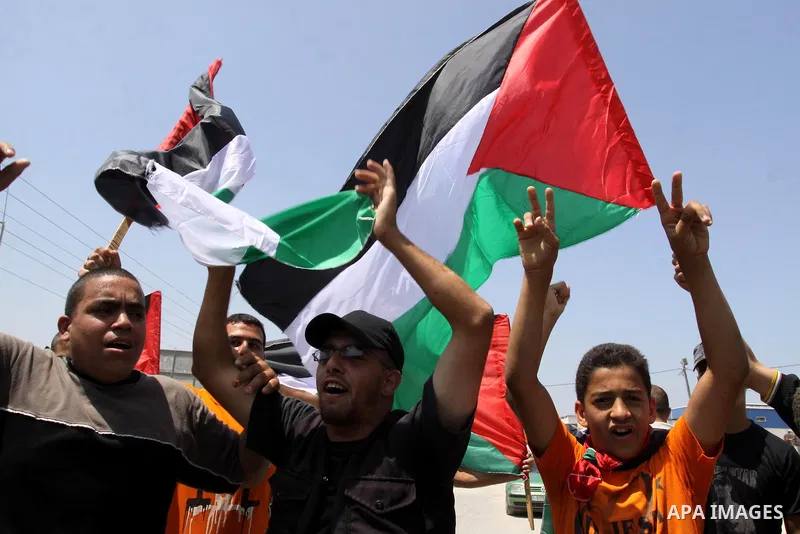 Palestinian protesters wave Palestinian national flags during a demonstration while Members of Hamas' security forces holds back protesters from reaching Erez border crossing in the northern Gaza Strip, on June 5, 2011,...
