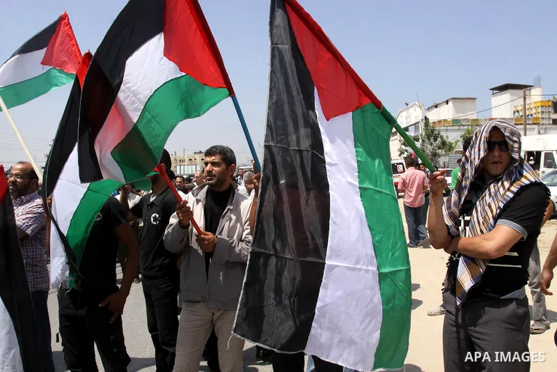 Palestinian protesters wave Palestinian national flags during a demonstration while Members of Hamas' security forces holds back protesters from reaching Erez border crossing in the northern Gaza Strip, on June 5, 2011,...