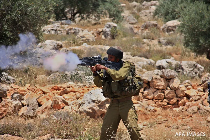An Israeli soldier fires tear gas canisters during clashes with Palestinian protestors following a demonstration against Israeli settlements in the West Bank village of Dair al-Hatab, east of Nablus, on June 5, 2011 as I...