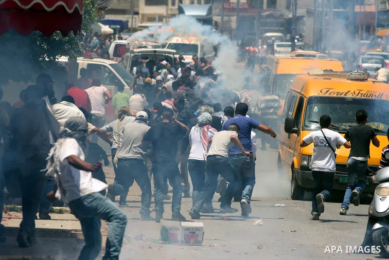 Palestinian demonstrators run for cover from tear gas canisters fired by Israeli soldiers during a protest marking the 44th anniversary of the Six Days War on June 5, 2011 at the Israeli-controlled Qalandia checkpoint be...