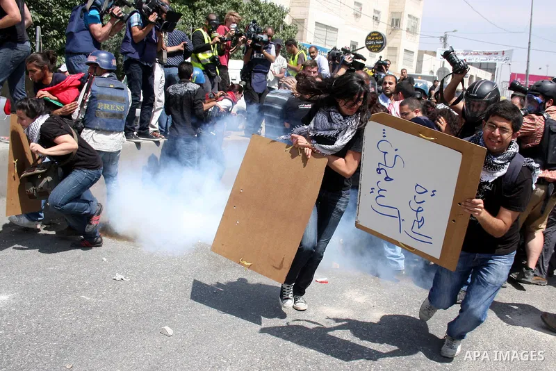 Palestinian demonstrators and foreign activists run for cover from tear gas canisters fired by Israeli soldiers during a protest marking the 44th anniversary of the Six Days War on June 5, 2011 at the Israeli-controlled...