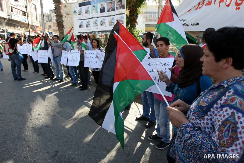 Palestinians shout slogans and hold their national flag as they demonstrate in the West Bank city of Ramallah on June 6, 2011 in respect to those who were killed a day earlier by Israeli soldiers during a protest marking...