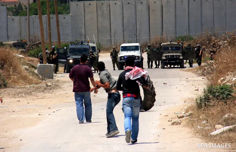 Palestinian youths throw stones at Israeli soldiers following a protest against Israel's separation barrier in the village Nazlet Issa north Tulkarm in the West Bank on June 7, 2011. Photo by Wagdi Eshtayah