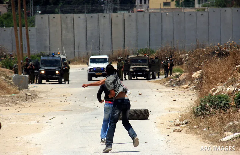 Palestinian youths throw stones at Israeli soldiers following a protest against Israel's separation barrier in the village Nazlet Issa north Tulkarm in the West Bank on June 7, 2011. Photo by Wagdi Eshtayah