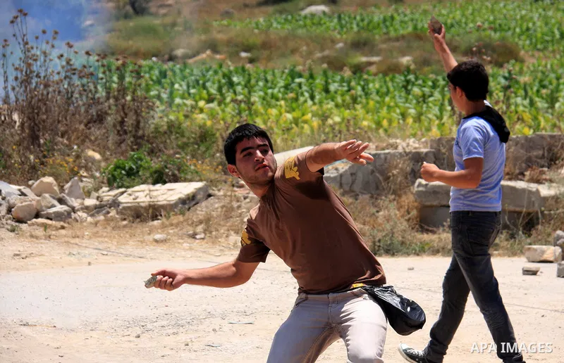 Palestinian youths throw stones at Israeli soldiers following a protest against Israel's separation barrier in the village Nazlet Issa north Tulkarm in the West Bank on June 7, 2011. Photo by Wagdi Eshtayah