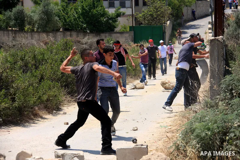 Palestinian youths throw stones at Israeli soldiers following a protest against Israel's separation barrier in the village Nazlet Issa north Tulkarm in the West Bank on June 7, 2011. Photo by Wagdi Eshtayah