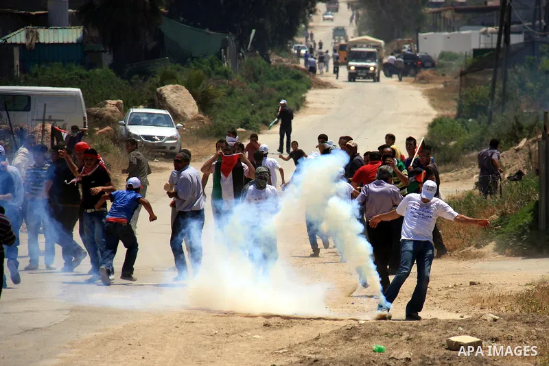 Palestinians youth, Israelis and foreign demonstrators run from tear gas fired by Israeli troops following a protest against Israel's separation barrier in the village Nazlet Issa north Tulkarm in the West Bank on June 7...