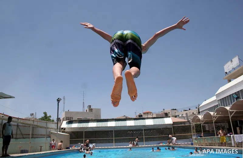 A Palestinian boy enjoys swimming in the swimming pool to feel relaxation after completion of their school examinations and the end of schools year, in the West Bank city of Hebron on June 08,2011. Photo by Najeh Hashlam...