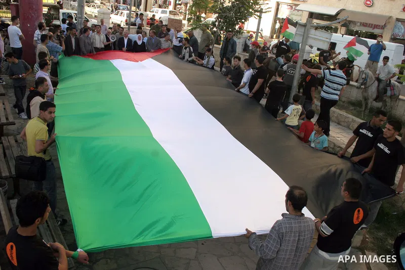 Palestinians hold up Palestinian National flag during a protest to mark the 44th anniversary of 'Naksa,' Arabic for setback, in the West Bank city of Hebron on June 09, 2011, as Palestinian activists in Jerusalem, the We...