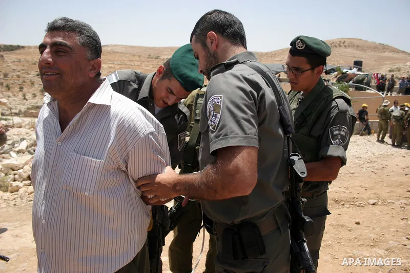 Israeli forces detain a protester during a demonstration by Palestinian and foreign peace activists against Israeli settlements in the West Bank village of Al-Tuwani, near Hebron, on June 10,2011. Photo by Najeh Hashlamo...