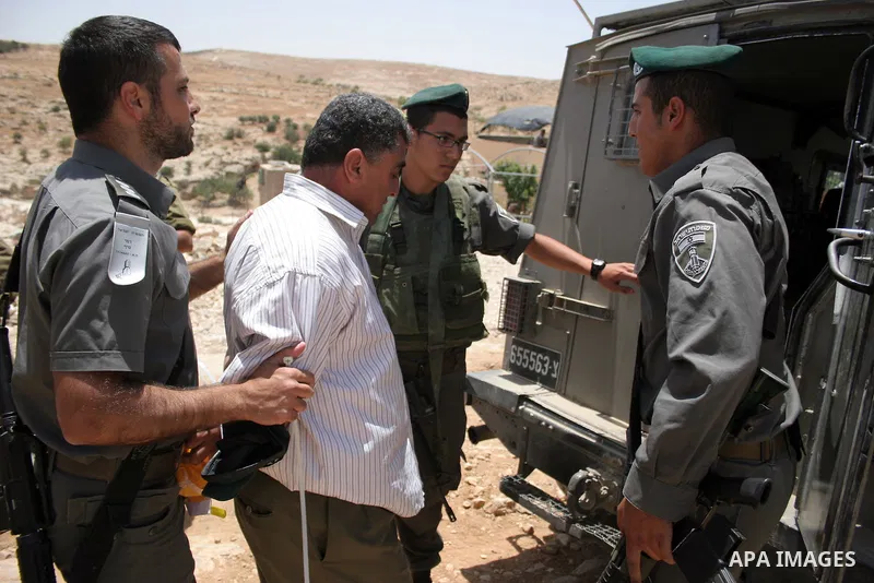 Israeli forces detain a protester during a demonstration by Palestinian and foreign peace activists against Israeli settlements in the West Bank village of Al-Tuwani, near Hebron, on June 10,2011. Photo by Najeh Hashlamo...