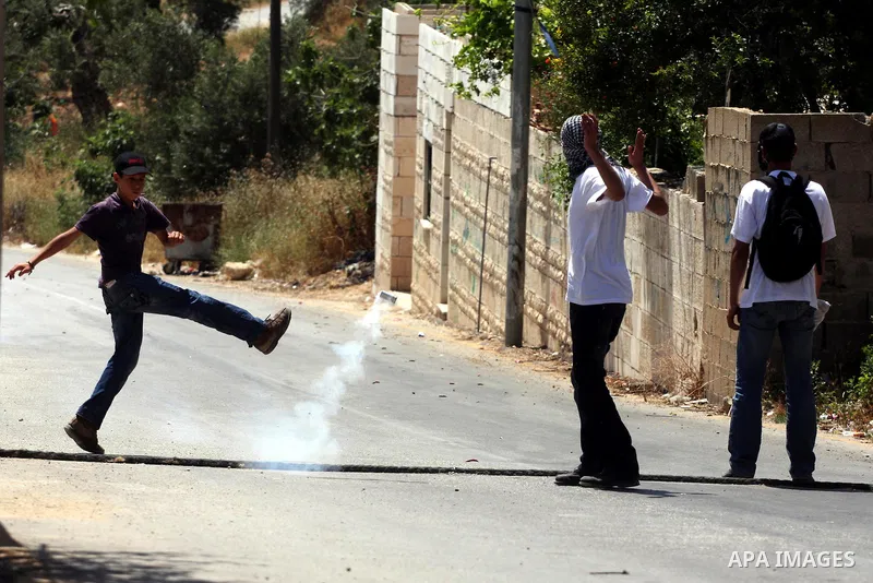 A demonstrator kicks back a tear gas canister fired by Israeli forces during clashes following a protest against the expropriation of Palestinian land, in the village of Nabi Saleh, in the Israeli-occupied West Bank, on...