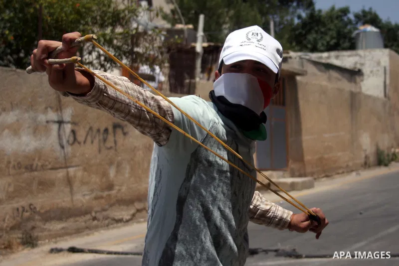 A demonstrator throws stones toward Israeli forces during clashes following a protest against the expropriation of Palestinian land, in the village of Nabi Saleh, in the Israeli-occupied West Bank, on June 10, 2011. Phot...