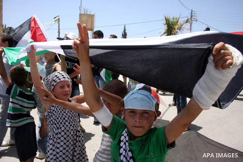 Demonstrators hold a Palestinian flag during a protest against the expropriation of Palestinian land, in the village of Nabi Saleh, in the Israeli-occupied West Bank, on June 10, 2011. Photo by Issam Rimawi