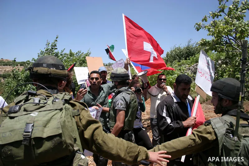 Israeli soldiers stand guard during a demonstration by Palestinian, Israeli and foreign activists against the destroy of farm lands used in the construction of Jewish settlements near the existing Israeli settlement of K...